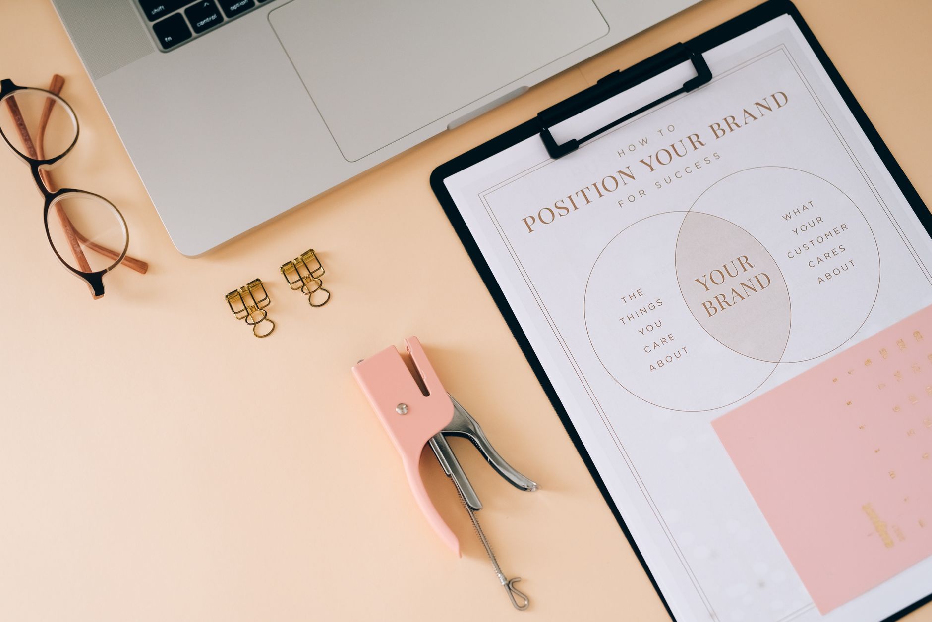 dolly parton capitalism: A flat lay composition featuring office essentials and a branding strategy clipboard on a modern wor