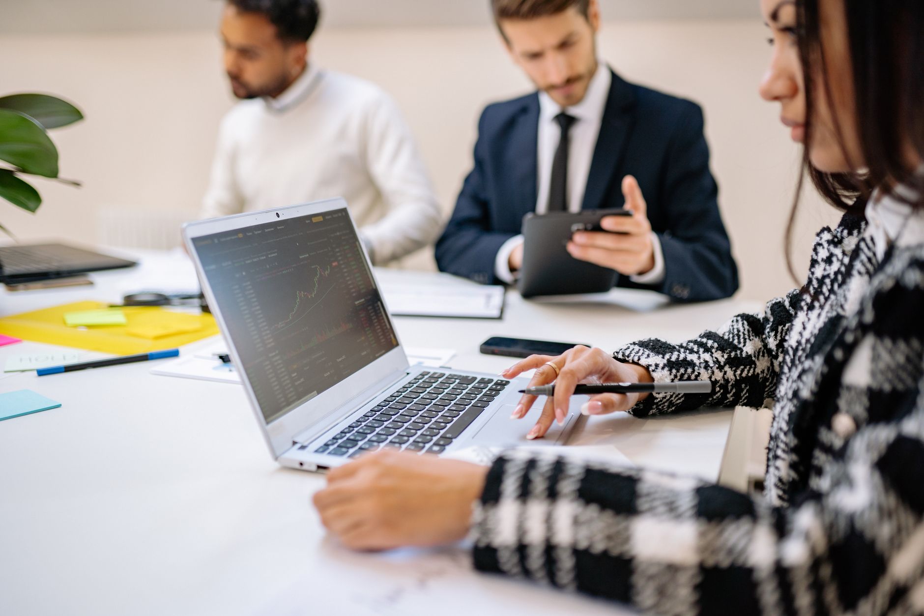trump ai force: Professional team working on stock market analysis with laptops and tablets in modern office setting.