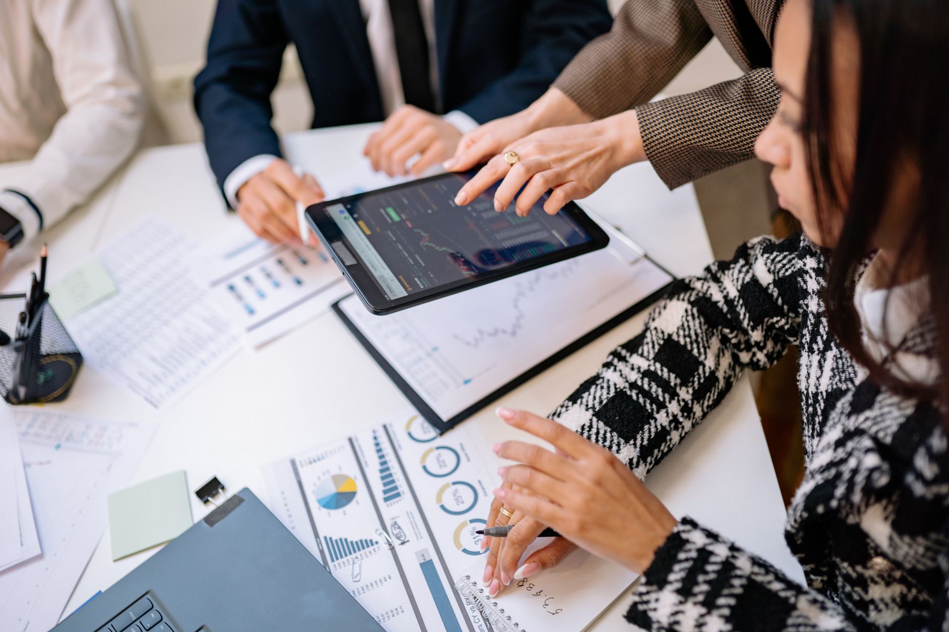uk economic outlook 2026: Business professionals reviewing analytics on a tablet during a meeting.